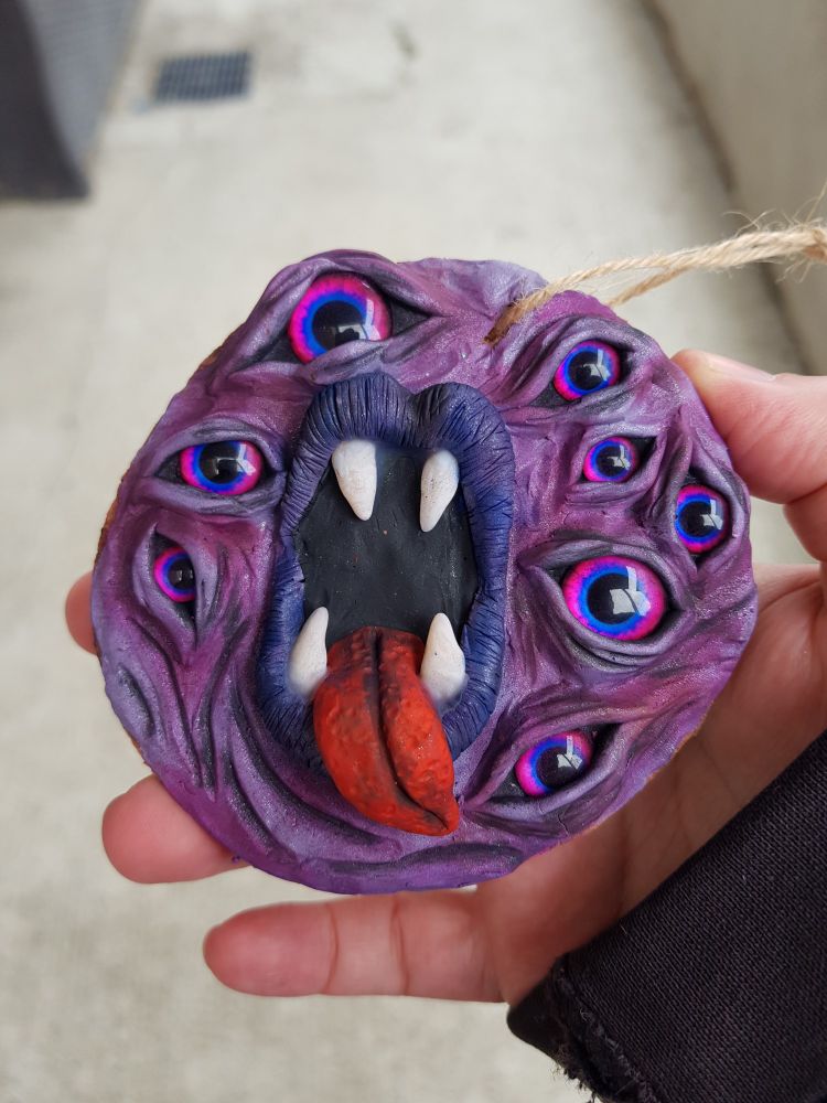 A demonic-looking wall hanging full of eyes and a wide-open mouth with its tongue sticking out.