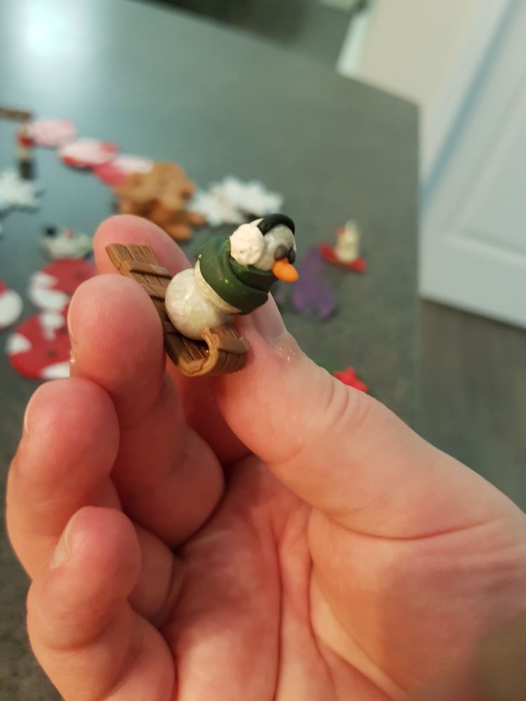 A snowperson on a luge about the size of the tip of a finger.