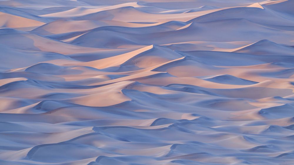 The last light of sunset casts warmth on the undulating sand dunes of Death Valley.