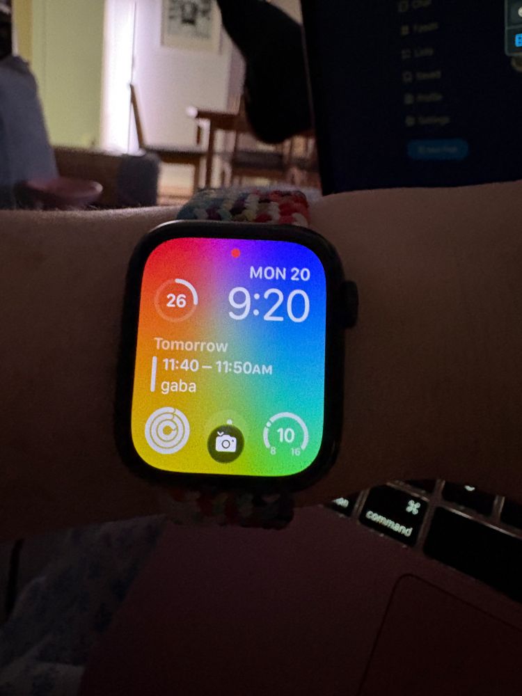 a rainbow gradient background on an apple watch with widgets showing battery life, date, time, next calendar item, exercise moves, exercise/camera, and weather