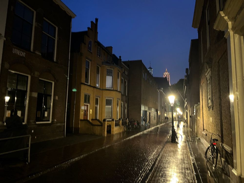 A small rainy side street in Utrecht in the Netherlands, lit by a couple of streetlights on one side