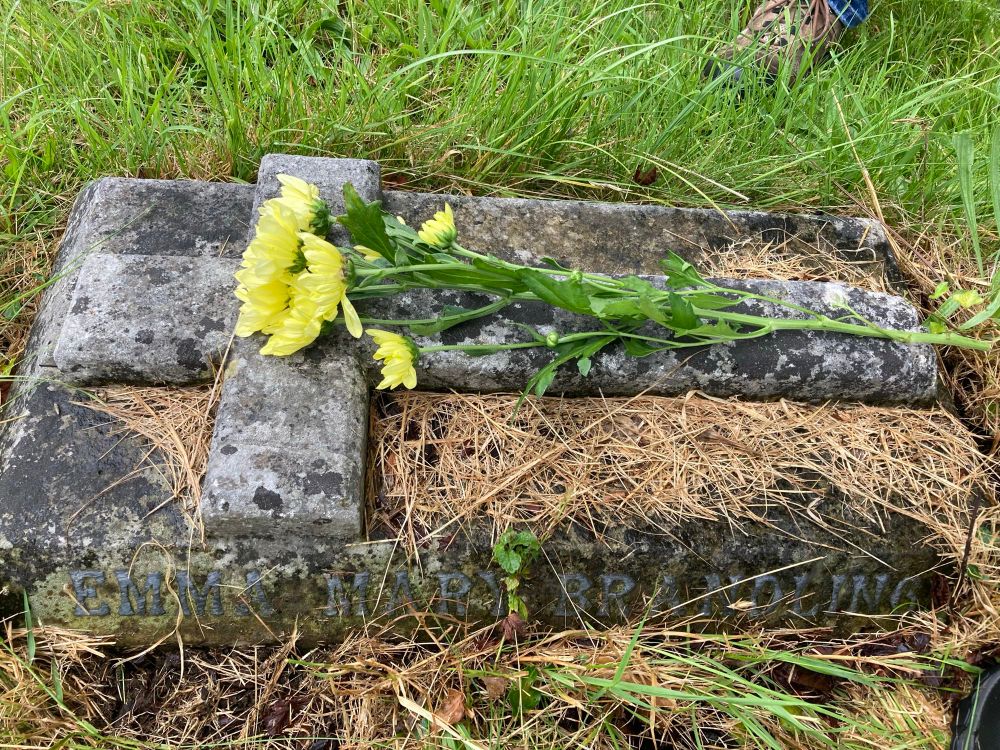 The small grave of a young girl with a simple cross on top
