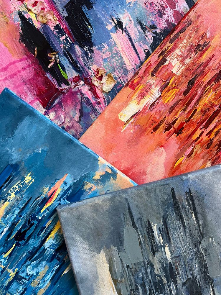 Four abstract paintings arranged in diagonal overlapping each other. The photo is cropped to show only a part of each. The colours of the paintings are (from top) pink, blue and purple, orange and red, blue and yellow, and muted blues and beige. Paintings by Ella Pesonen. 