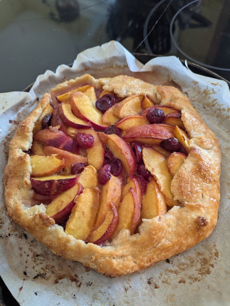 A peach and cherry galette on a piece of parchment paper 