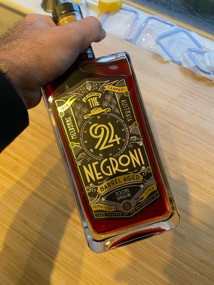 A bottle of pre-mixed barrel aged negroni. The label is in a black and gold art deco style.