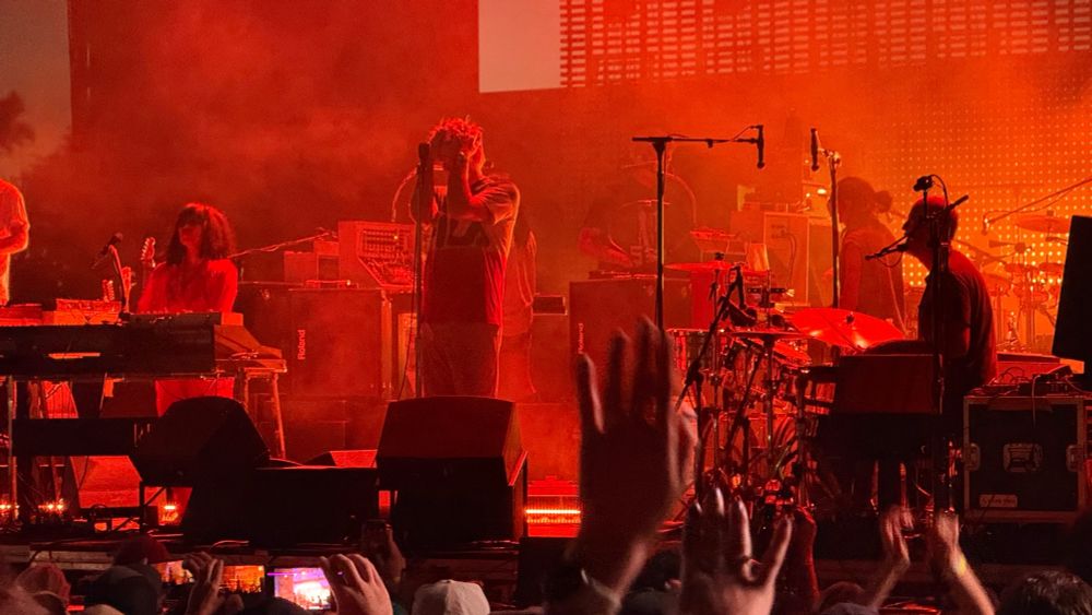 James Murphy from LCD Soundsystem, on stage, holding his hair or something. Very red photo.
