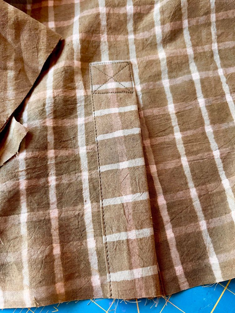 A sleeve placket on an in-progress long sleeved button down shirt. It’s made of a greenish brown and white grid block-printed cotton fabric  