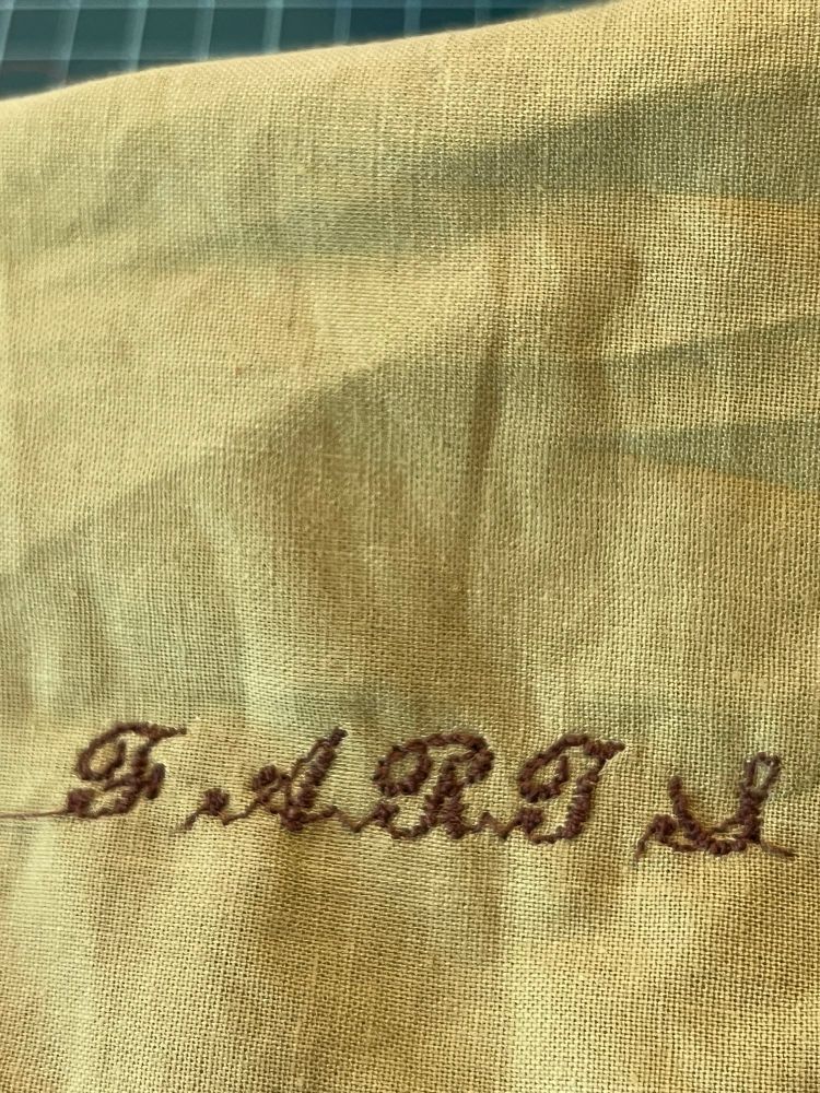 A piece of fabric with cursive sewing machine embroidery that says “FARTS”