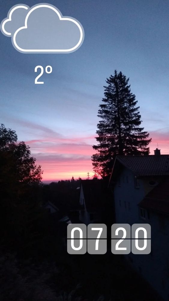 Sonnenaufgang in verschiedenen rosarote Tönen in hellorange untergehend
Davor große Bäume und Wohnhäuser 
2 Grad um 7:20 Uhr