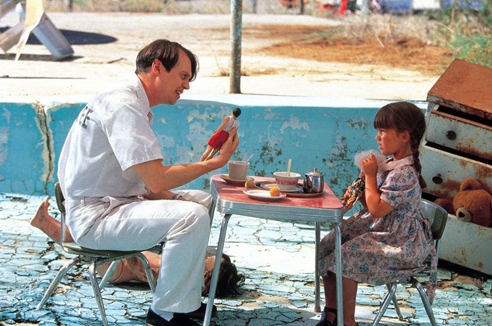 Scene from the movie "Conair" with a prisoner sitting at a table playing dolls with a small child.
