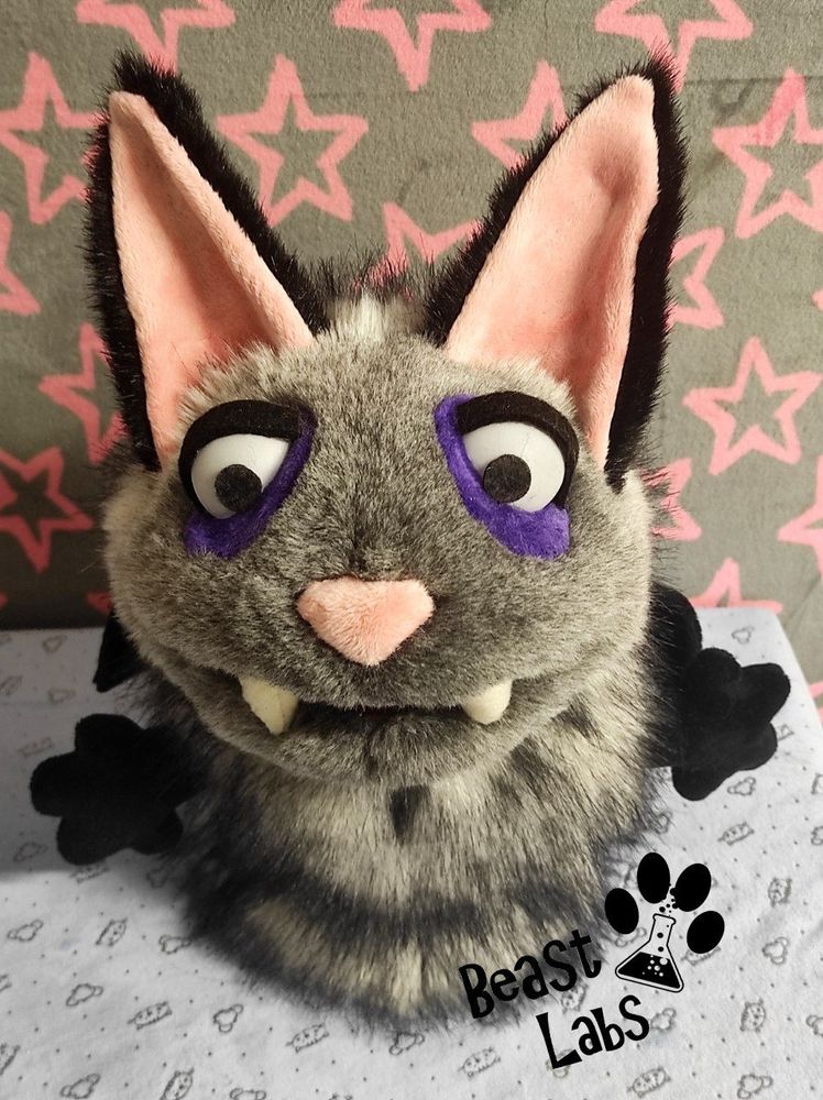 Picture of a grey and black bat-cat hand-puppet. This is the 3/4 top down view.