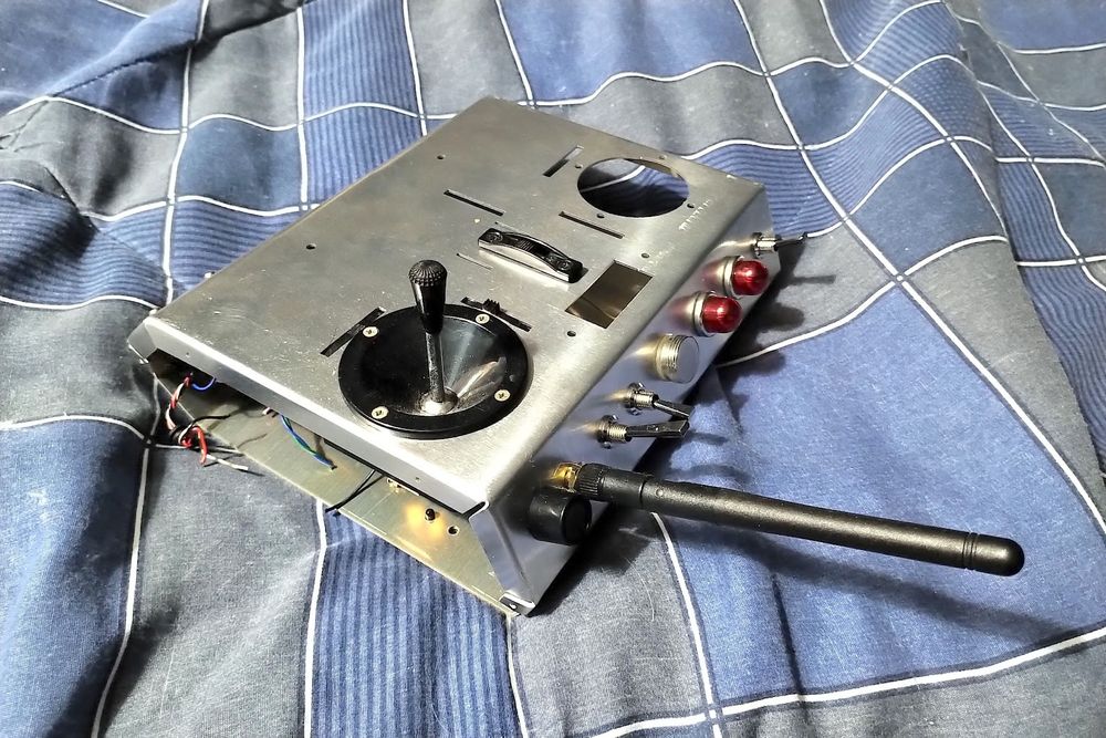 Partly assembled transmitter matching the rendering, with a joystick, antenna, and some switches and lights installed.