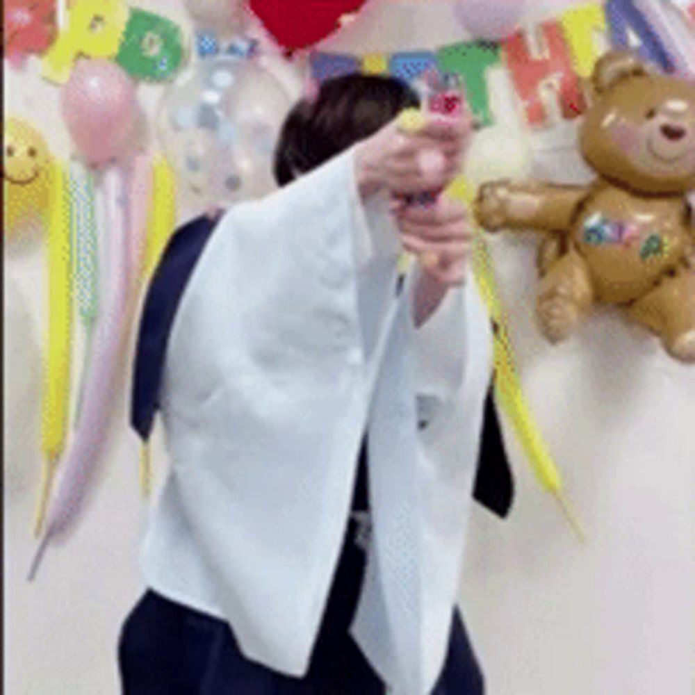 a person is standing in front of a teddy bear and balloons