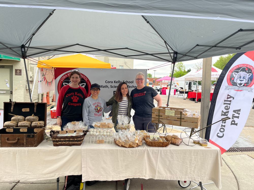 A team of awesome parents stands behind a table of wrapped baked goods at last year’s bake sale