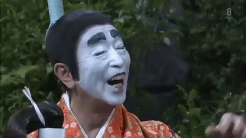 a man with white paint on his face is wearing a kimono .