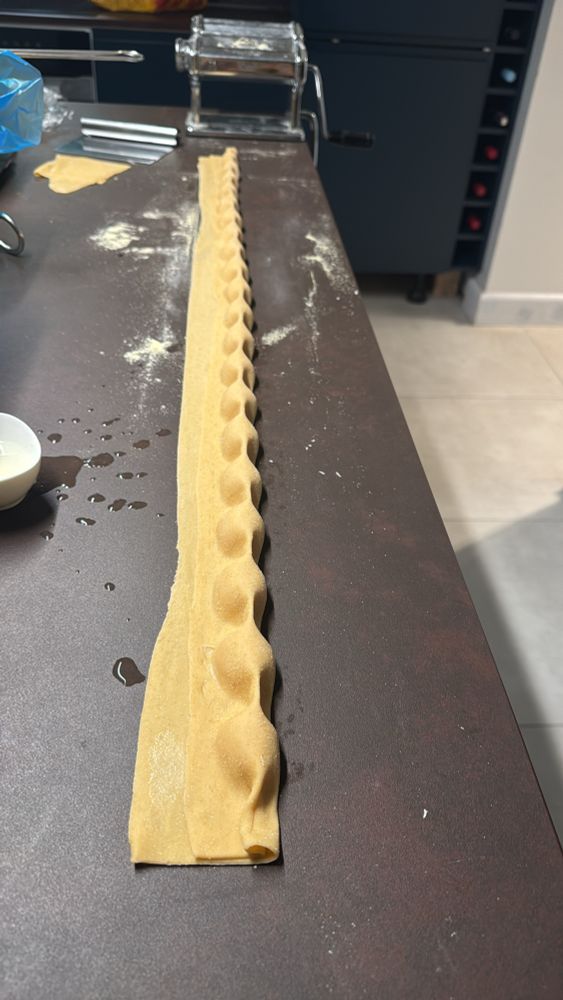 A photo of pasta having been rolled up and shaped into a long log of agnolotti