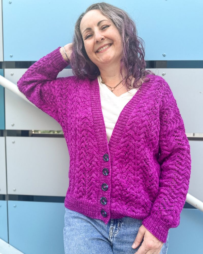 Woman standing wearing bright purple cardigan and jeans