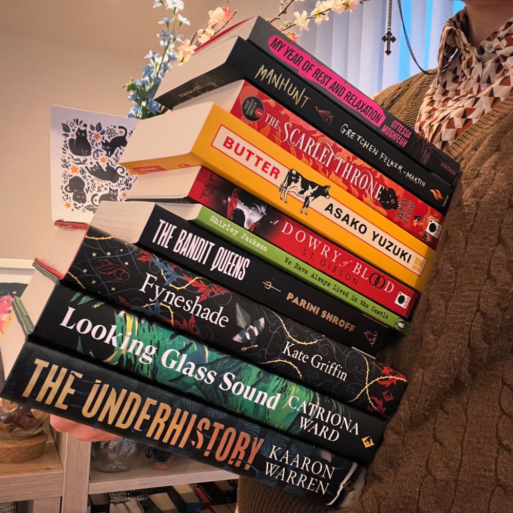 Angie holding a stack of books they love.