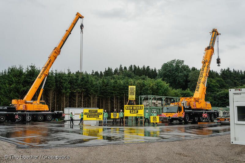 Aktivistinnen halten gelbe Banner mit der Aufschrift „Kein neues Gas“. Sie stehen auf einer Baustelle zwischen zwei Kränen.