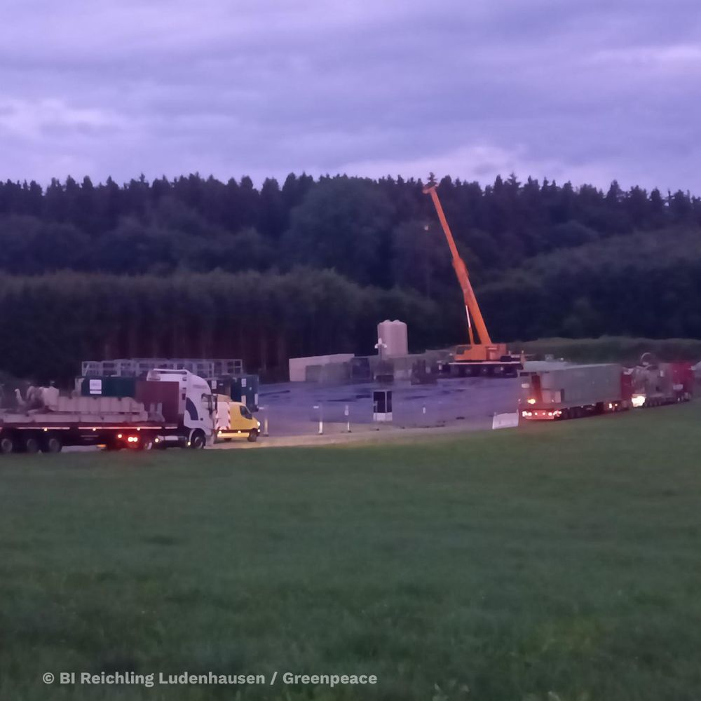 Nachtbild, LKWs fahren auf eine Baustelle, ein gelber Kran ist zu sehen.