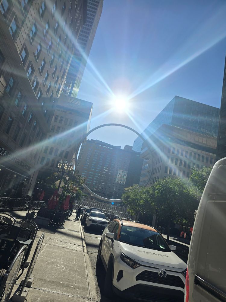 Picture of a metallic ring structure in between city building.  Montreal