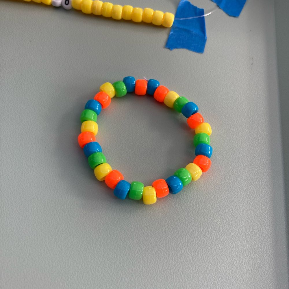 A bracelet made with a yellow-green-blue-orange bead pattern.