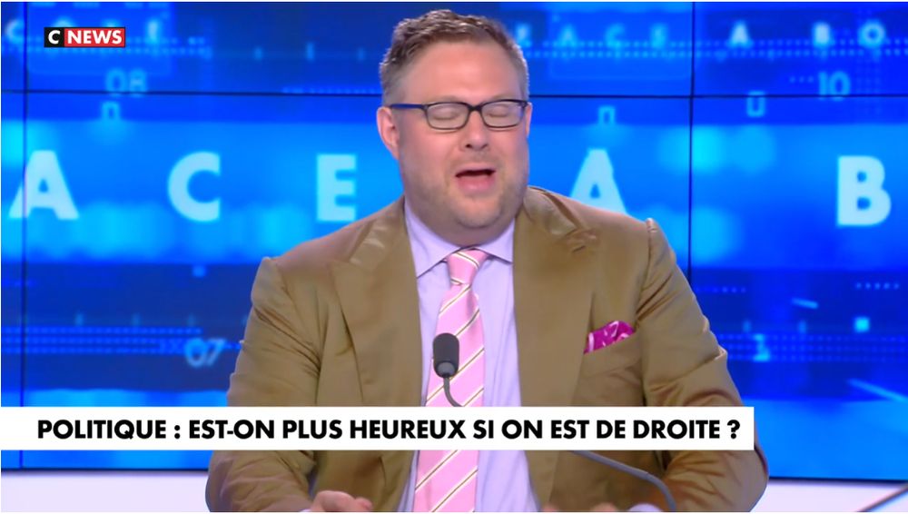 On voit le chroniqueur Mathieu Bock-Côté, la bouche ouverte et les yeux fermés. Il a l'air content de lui. Il porte une chemise mauve avec une cravate rose. Le texte dit: "Politique, est-on plus heureux si on est de droite?"