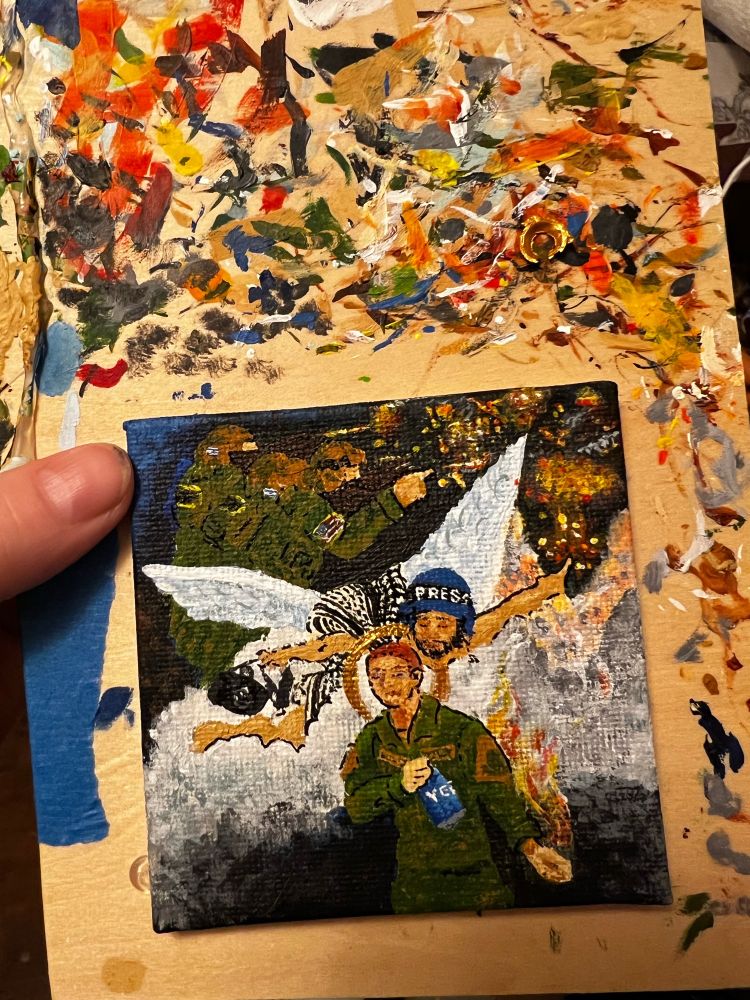 A tiny painting in tribute to Aaron Bushnell. Palestine burns in the background, while an angel, holding a camera and wearing a press helmet, points to the carnage. Acrylic on canvas board, 2” x 2” 