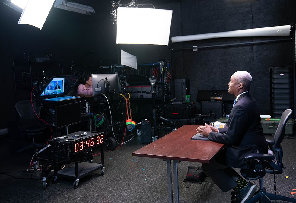 Atlanta Fed president and CEO Raphael Bostic sits at a table in a studio talking to a television monitor while live on air with Fox Business Network anchor Liz Claman.
