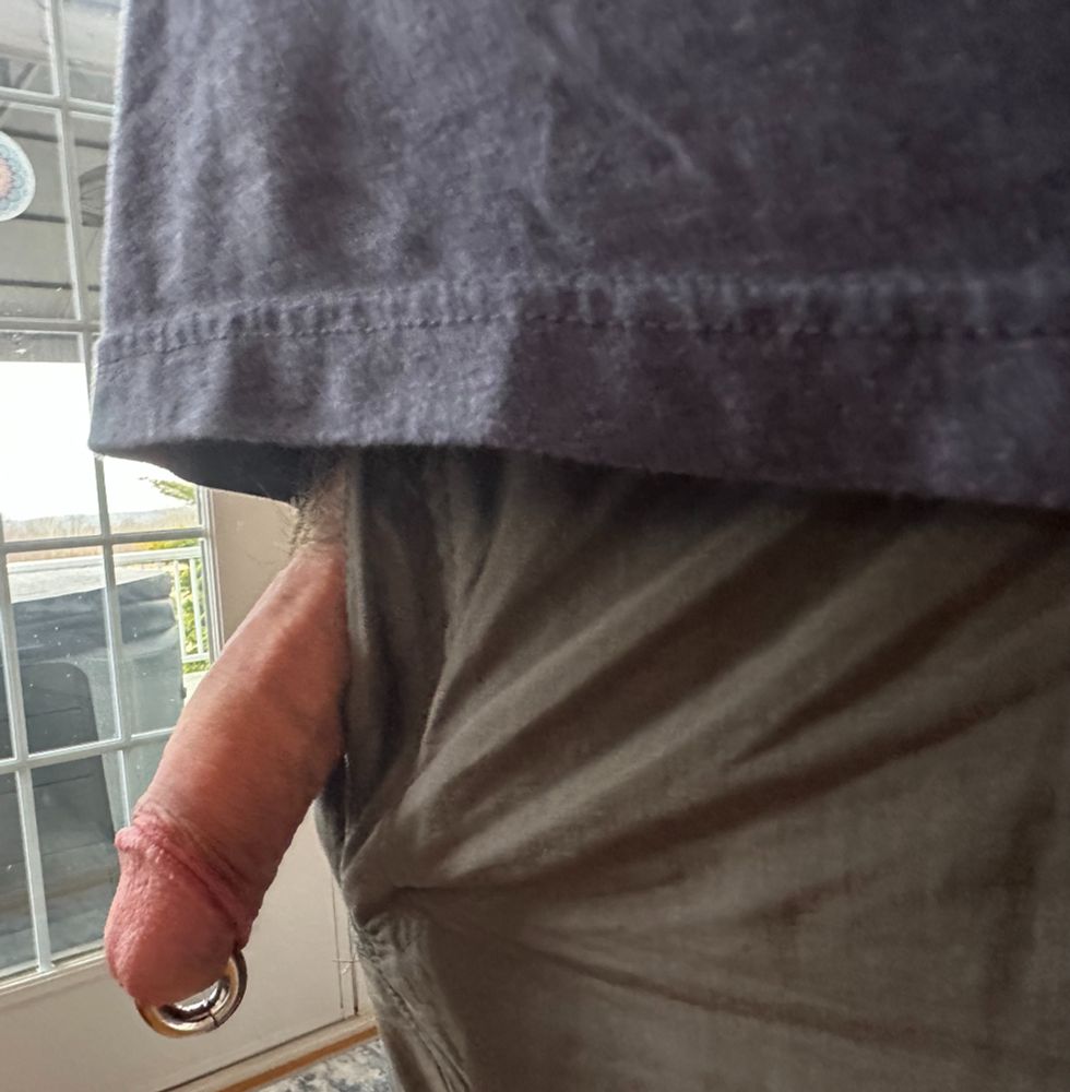 Close-up of dude wearing a gray t-shirt and khaki pants with a fat pierced cock hanging out of his fly.