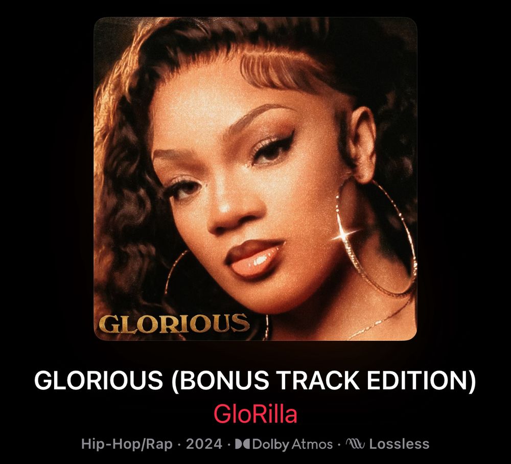 A screenshot of the cover for GloRilla’s album, GLORIOUS. A close-up picture of GloRilla in color is featured on the cover. Her dark hair is wavy with edges laid, and she’s wearing large gold hoops. Her face is tilted slightly, so there’s a camera glare off the hoop in her left ear. 