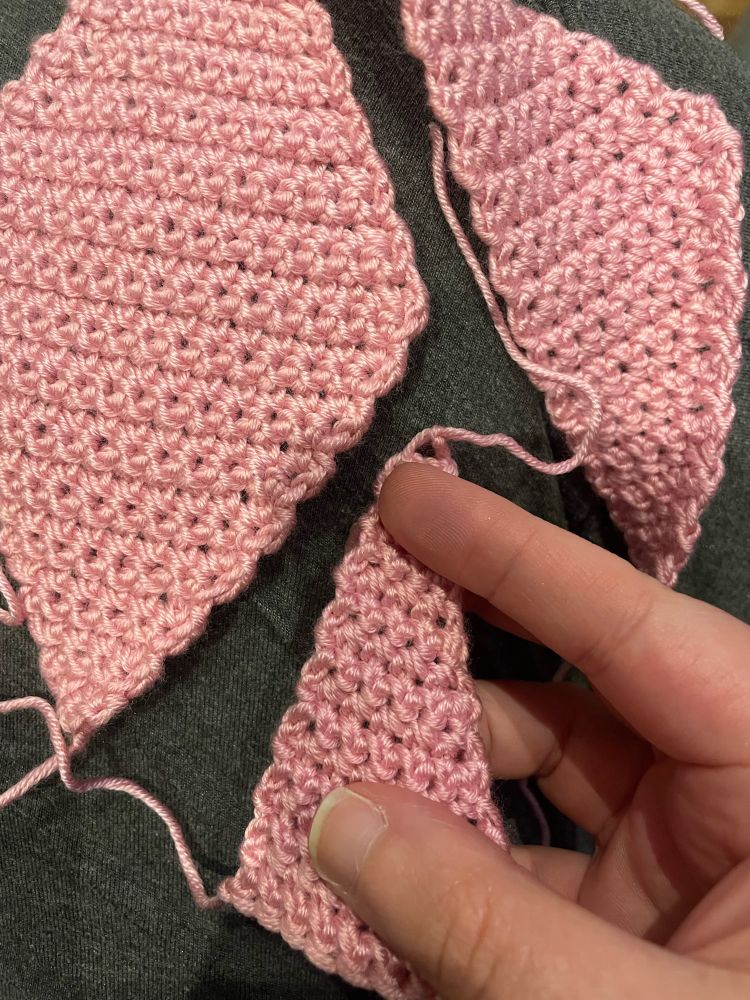 Pink yarn crocheted into one rhombus and two triangles of different proportions 