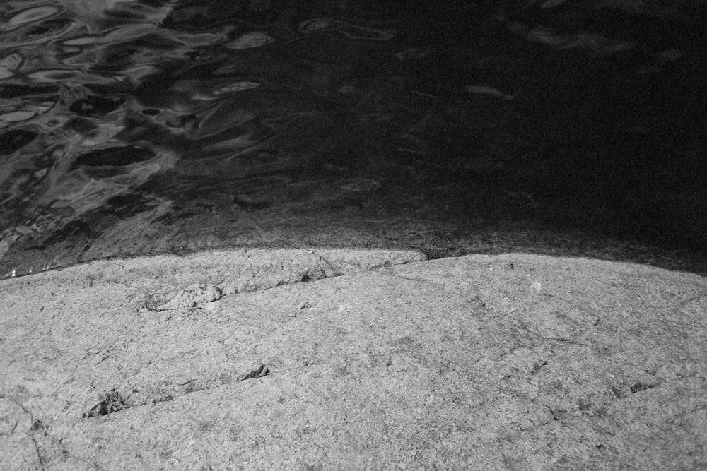 Closeup of the shoreline of a lake, where rock meets water.