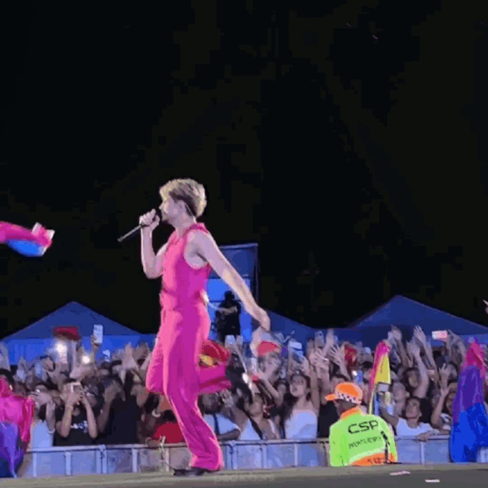 a woman in a pink jumpsuit stands on a stage in front of a crowd and a sign that says csr