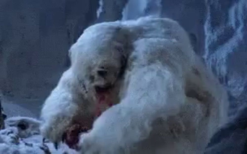 a large white furry animal with blood coming out of its mouth is sitting in the snow .