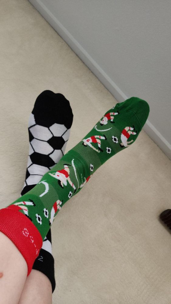 football socks, field and players on the left foot, soccer ball pattern on the right