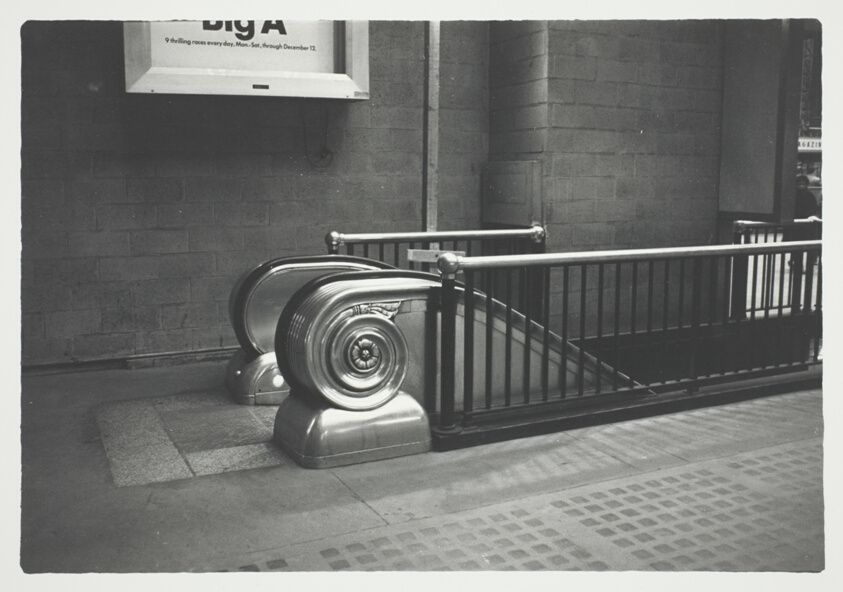 B&W photo of an escalator, with elaborate scroll-like elements