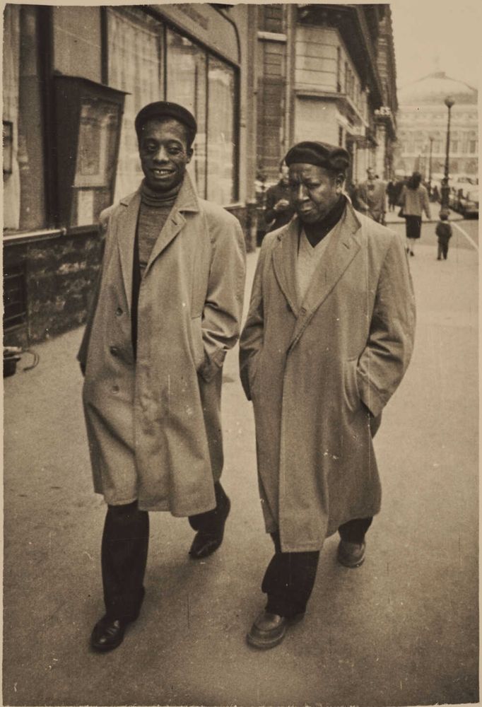 Photo of James Baldwin and painter Beauford Delaney walking side by side on a street in Paris