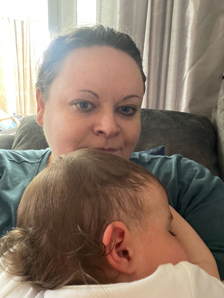 Me, with a cutie baby asleep. You can see her curly brown hair 