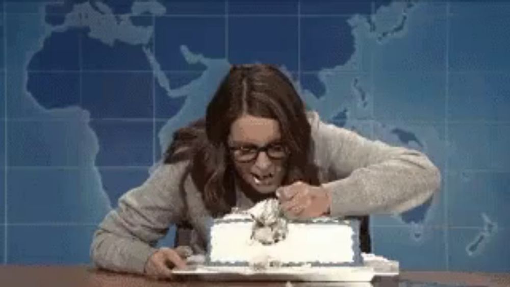 a woman is sitting at a table eating a cake with a map in the background