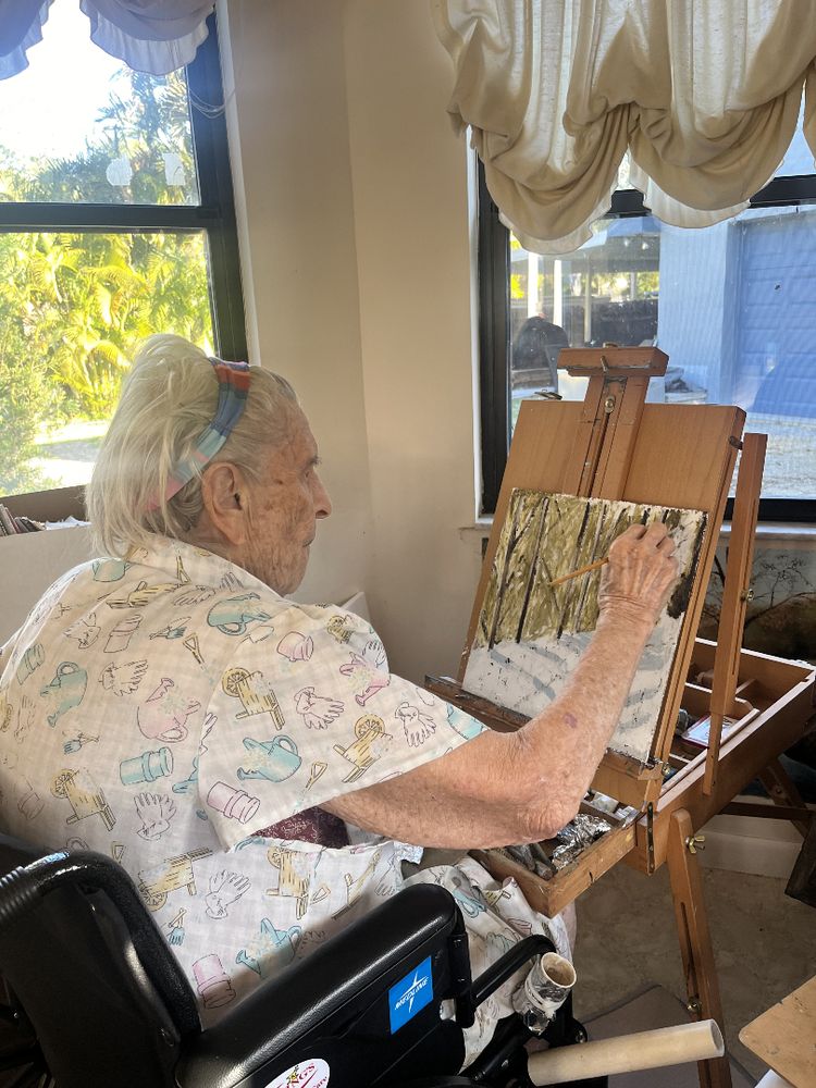 96 year old artist, Ruth, paints a landscape scene on a panel for the library. 