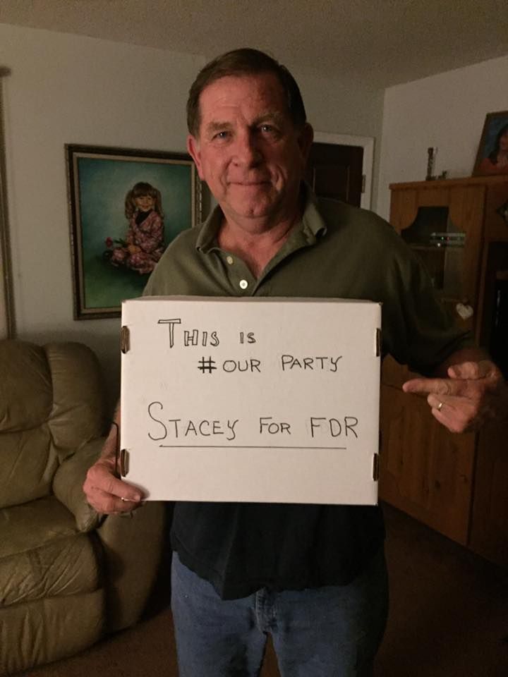 Man inside home holding sign that say "This is #ourparty STACEY for FDR