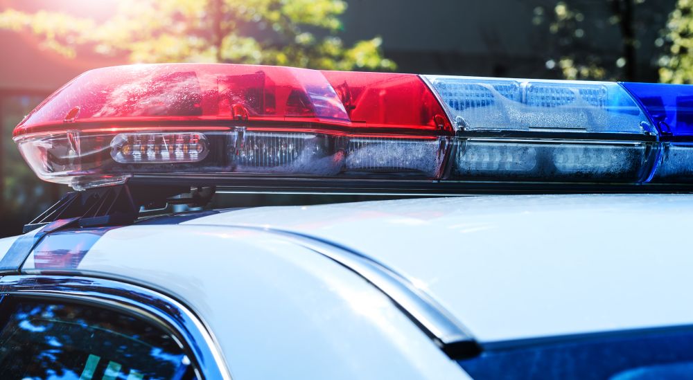 [Image: A closeup of red, white, and blue lights on the roof of a police car.]
