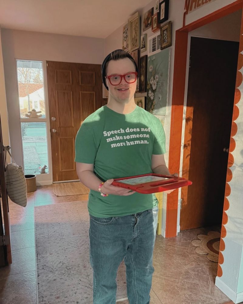 AAC user Jackson Schroeder sports a green CommunicationFIRST T-shirt featuring a quote by our Board Chair Jordyn Zimmerman: “Speech does not make someone more human.”
