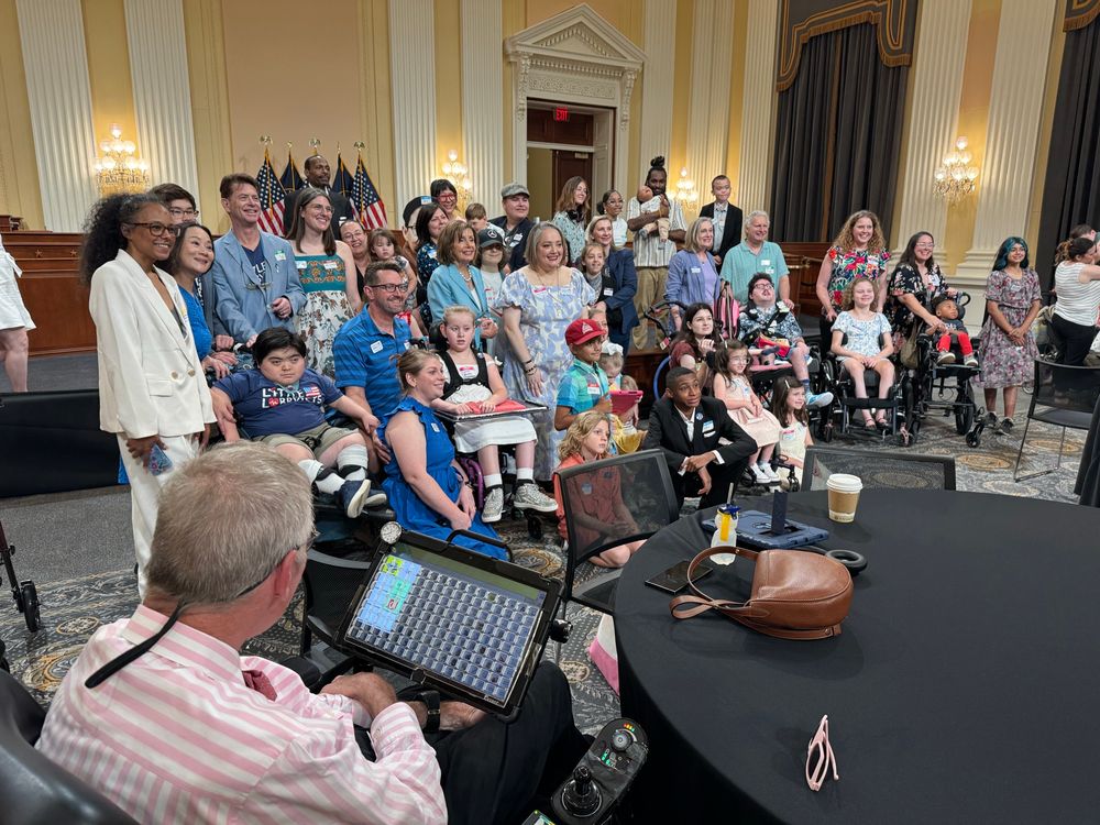 A group of medically complex children pose with House Speaker Emerita Nancy Pelosi, with Bob Williams in the foreground, looking on