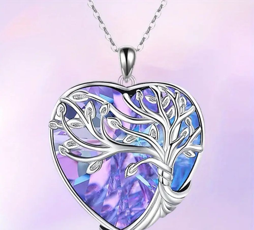The pendant has a silver tree with a purple background. The pendant is heart shaped. 