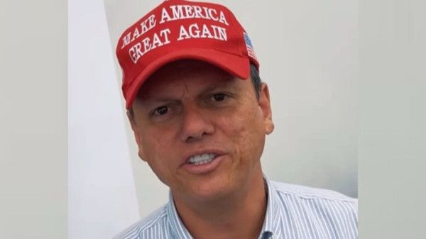 Imagem do governador de São Paulo, Tarcísio Freitas, usando um boné com a bandeira dos Estados Unidos na lateral e a frase "Make America Great Again", slogan da campanha de Donald Trump à Presidência dos EUA, na aba.