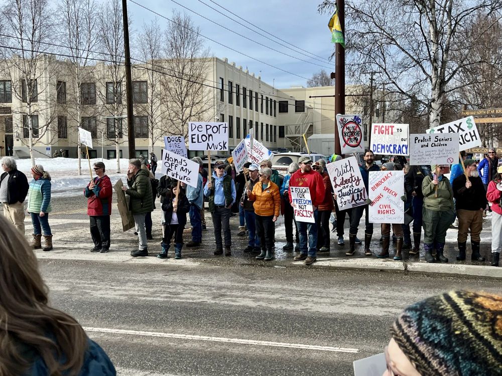 People standing on the sidewalk in Fairbanks holding signs in support of taking back our county.