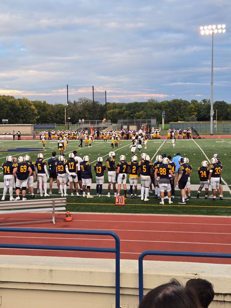 A third down play on the football field with the two teams benches in the fore and back grounds.