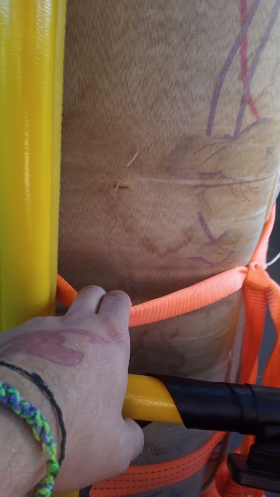 Minha mão segurando uma fita que prende um colchão de solteiro dentro de um busão 